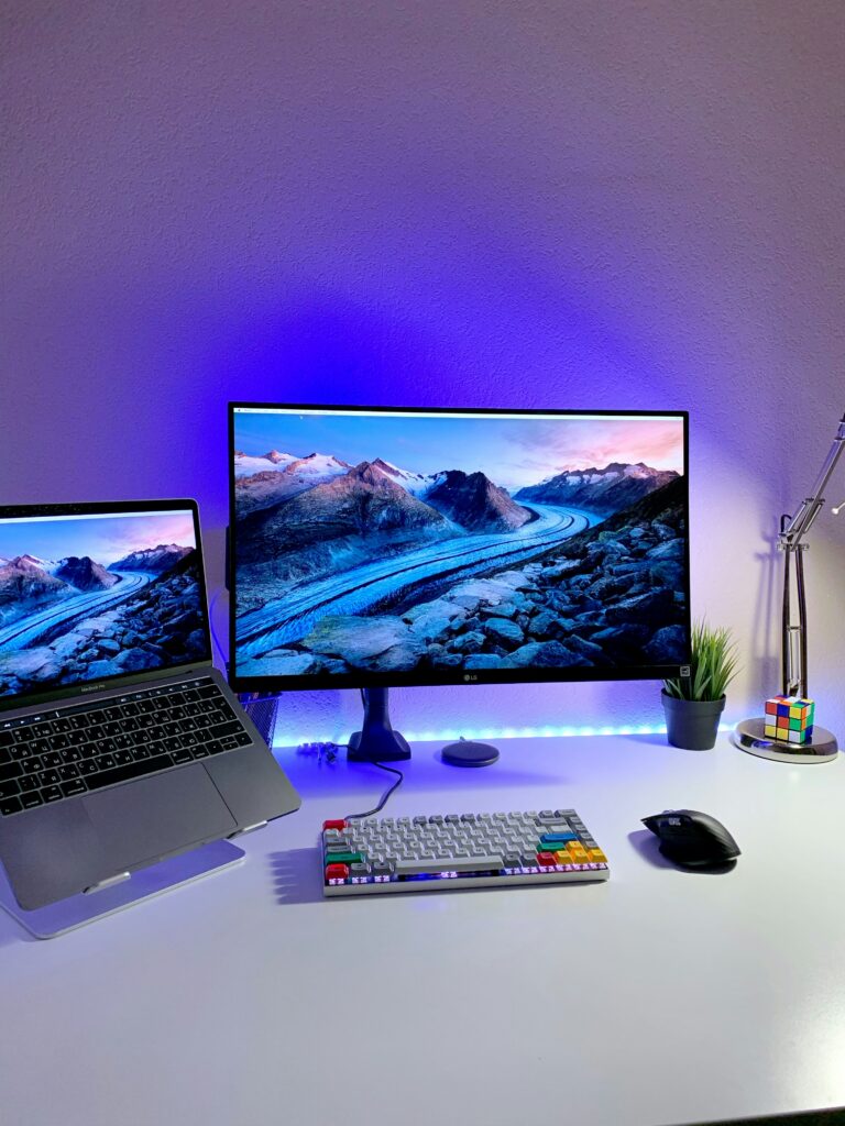 Laptop and monitor set up side by side on a desk with keyboard and mouse, illustrating the laptop vs mini PC choice for home use